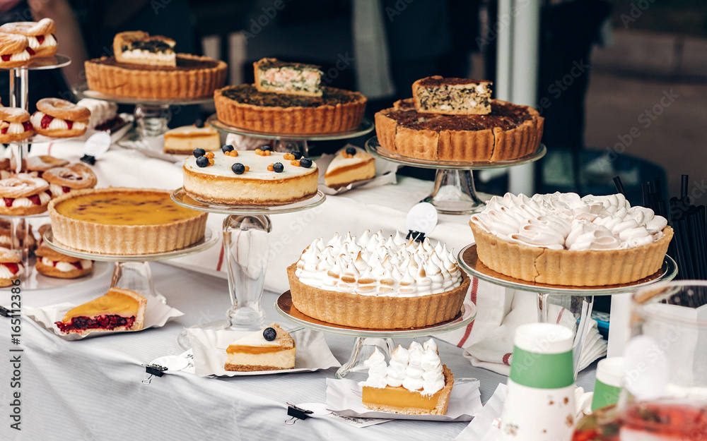 delicious cakes and pie with whipped cream on table at street food festival. candy bar with tasty sweets, catering at wedding reception. open kitchen outdoors. summer picnic
