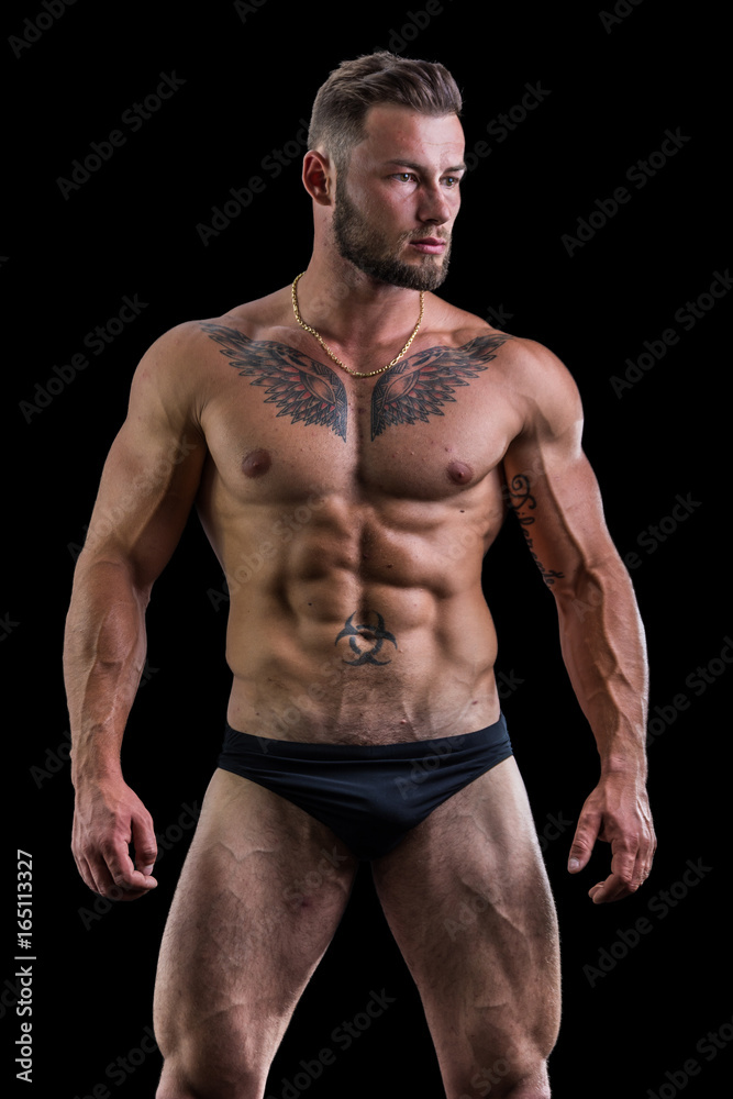 Handsome shirtless muscular man in briefs, standing, isolated on black background Handsome shirtless muscular man in briefs, standing, isolated on black background