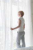 Young woman looking at window in the morning. Side view