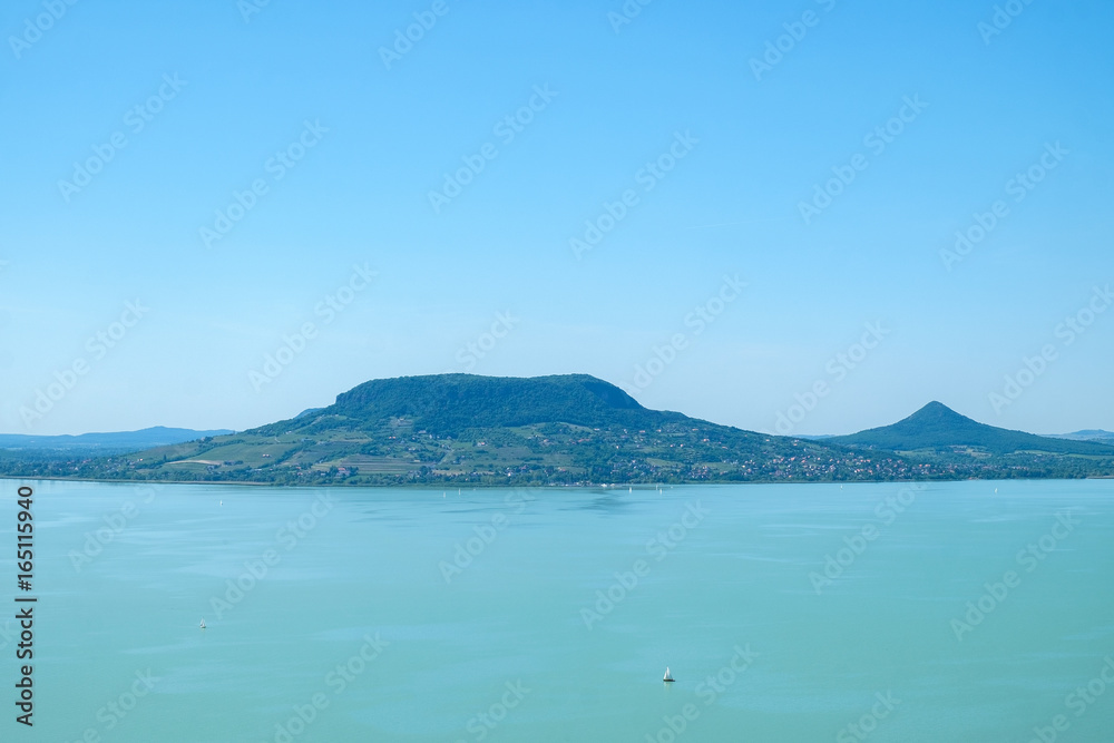 sailboat on water, fameus Badacsony hill in background - summertime and vacation at Balaton lake