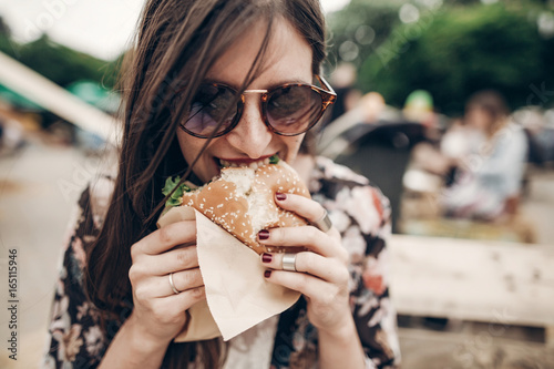 Εκτύπωση καμβά stylish hipster woman eating juicy burger