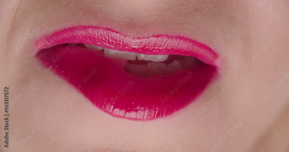 Attractive Female with Red Lipstick Bites Lip Close Up. an extreme close up of a females mouth with red lipstick biting lip in a sexy fashion
