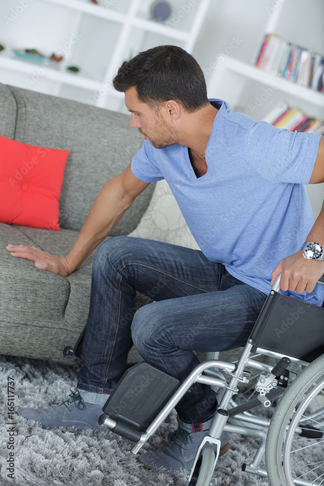 disabled man transferring himself to the sofa