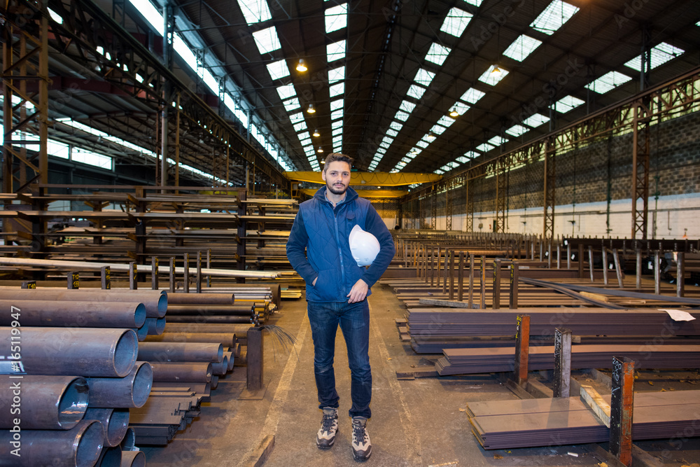 male worker stood in warehouse stocking metal lengths male worker stood in warehouse stocking metal lengths