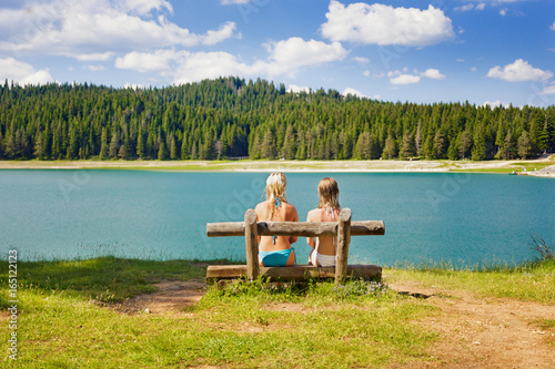 two girls on a bench near the lake