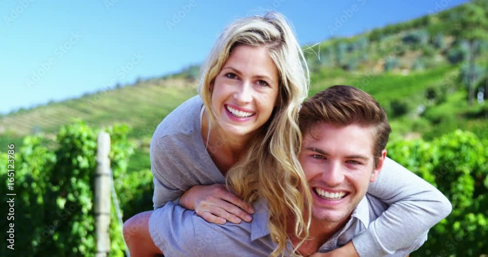 Portrait of happy man giving woman piggy back in vineyard Portrait of happy man giving woman piggy back in vineyard