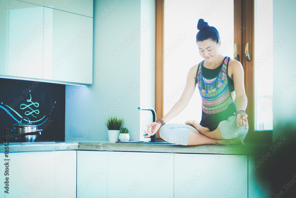 Young beautiful woman sitting at the kitchen table in the lotus position. Woman. Yoga Young beautiful woman sitting at the kitchen table in the lotus position. Woman. Yoga