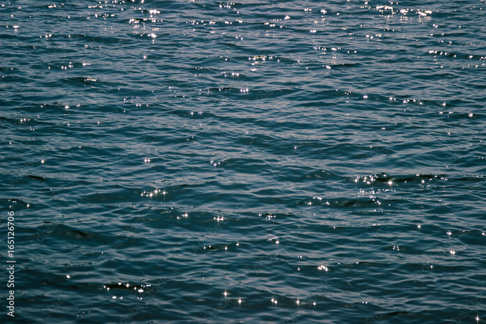 Reflections of the sun in the wavy blue sea surface Reflections of the sun in the wavy blue sea surface
