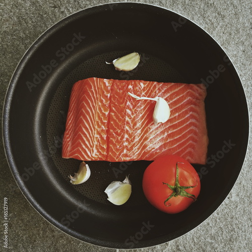 Salmon with garlic and tomato on plate 