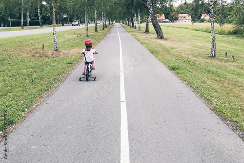 Little girl riding bike on lonely road 