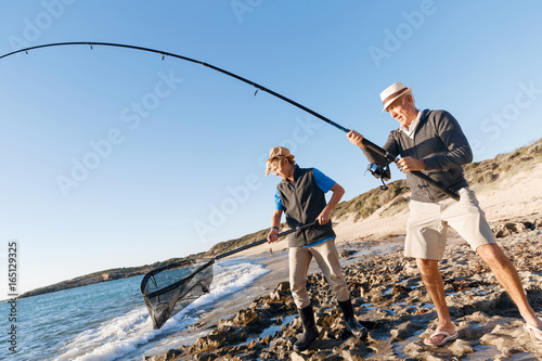 Senior man fishing with his grandson