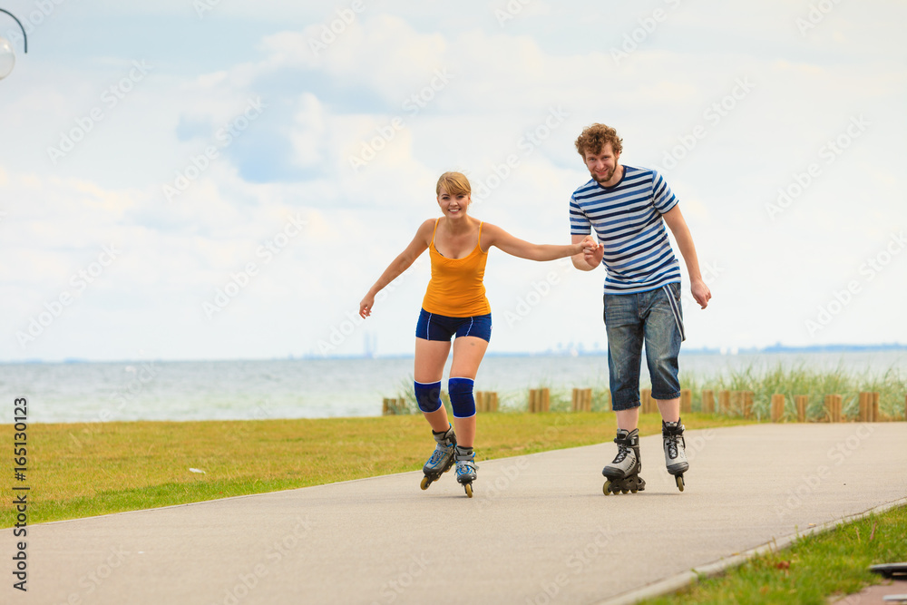 Fototapeta premium Young couple on roller skates riding outdoors