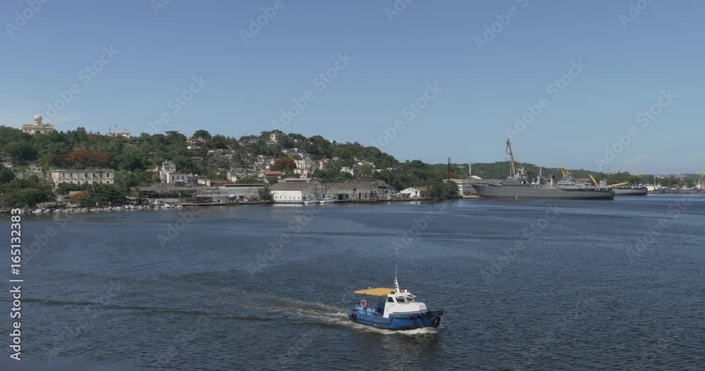 A small tug boat travels past the Havana landscape and military ships. Shot at 48fps. A small tug boat travels past the Havana landscape and military ships. Shot at 48fps.