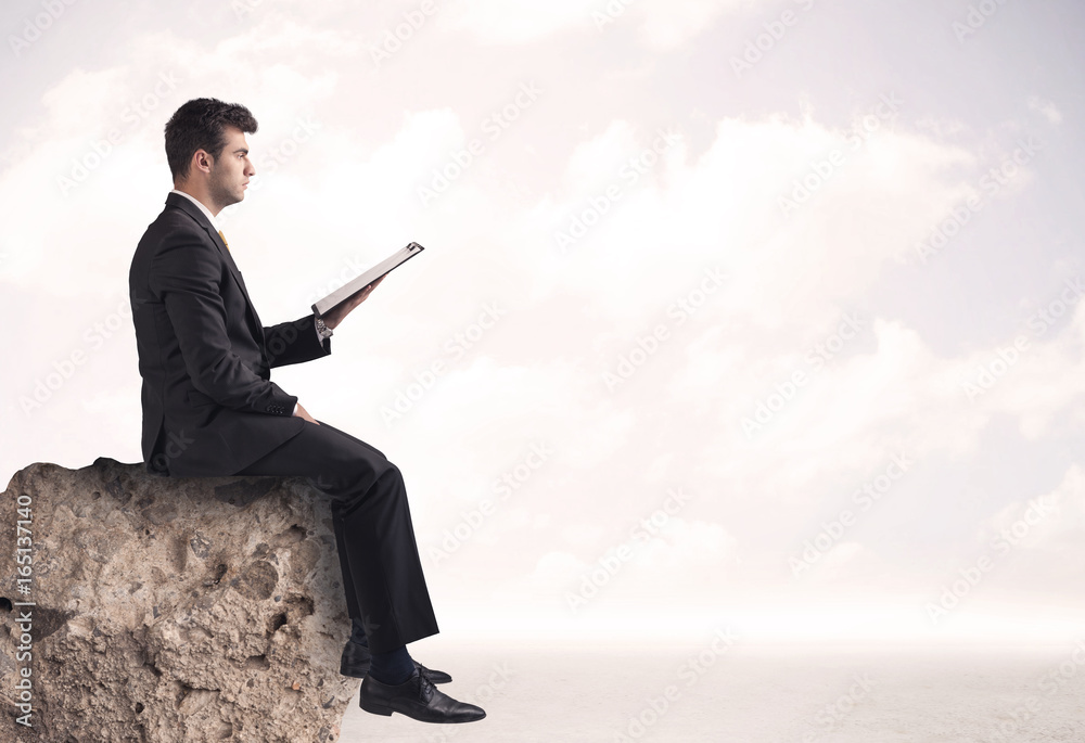 Business man sitting on stone edge Business man sitting on stone edge