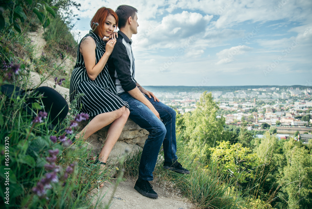 Fototapeta premium couple sitis on the hill with ponaramic view