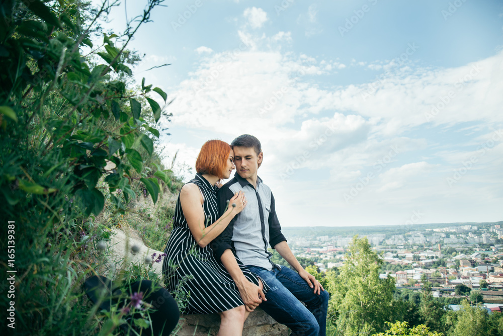 couple sitis on the hill with ponaramic view