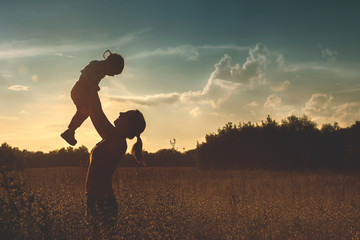 Silhouette of a young mother and her little daughter at sunset