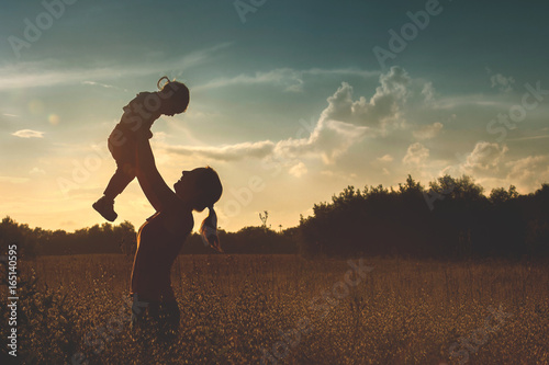 Silhouette of a young mother and her little daughter at sunset photo