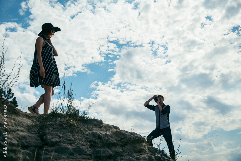 young couple on the hill, man taking picture of his girlfriend young couple on the hill, man taking picture of his girlfriend