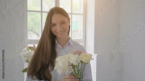 Young smiling florist girl with bouquet at flower studio