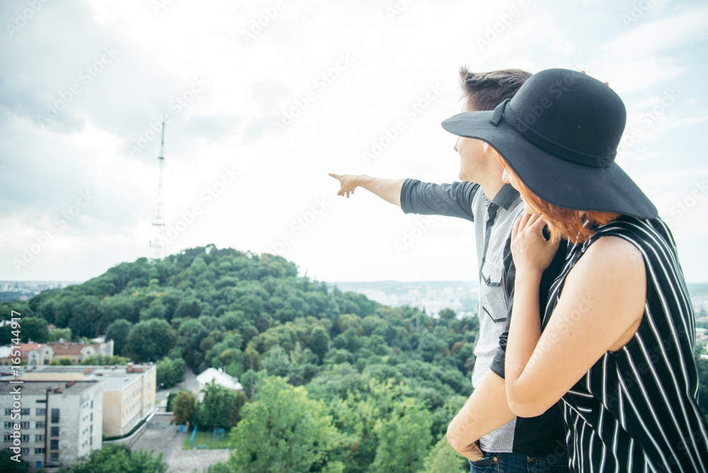 Fototapeta premium couple standing on the hill hugging and looking on city view