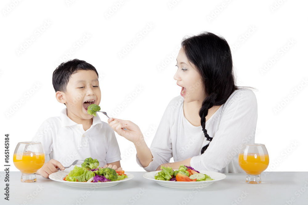Pretty mother feeding her son on studio Pretty mother feeding her son on studio
