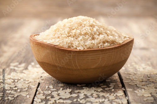 Uncooked parboiled rice in a bowl on wooden table
