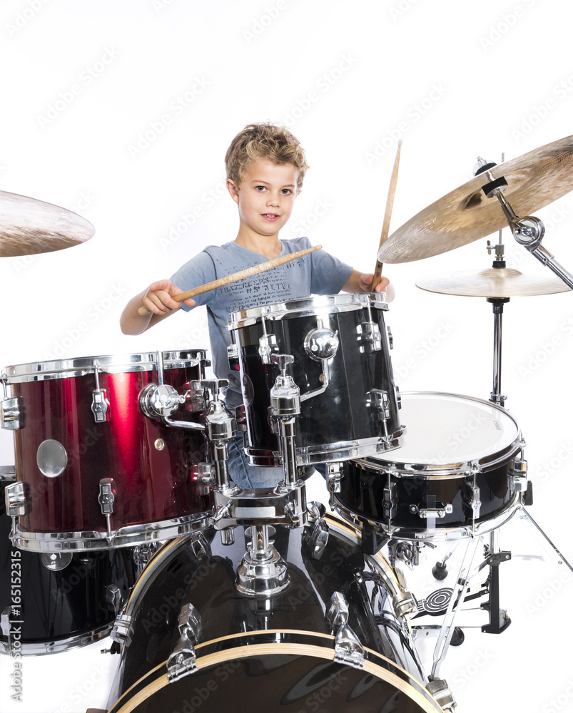 Fototapeta premium young caucasian boy plays drums in studio against white background