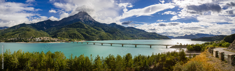 Panoramic view of Serre-Poncon Lake with Savines-le-Lac and its bridge with the Grand Morgon mountain peak in summer. Hautes-Alpes, Durance Valley, PACA Region, Southern French Alps, France