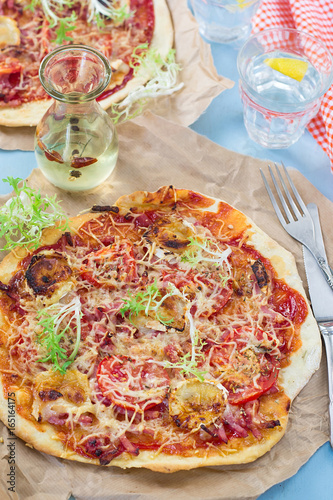 Healthy pizza with thin dough, ham and tomatoes