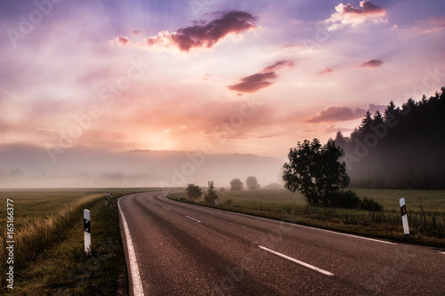 Empty road at morning sunrise leading into the mist. Concept of beginning, hope and freedom.