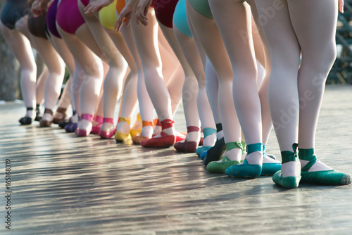Ballerinas feet dancing on ballet shoes with several colors on stage during a performance.