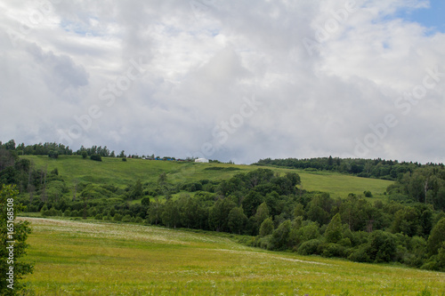 Summer landscape. Field, forest and sky. Landscape of the Russian remote places.