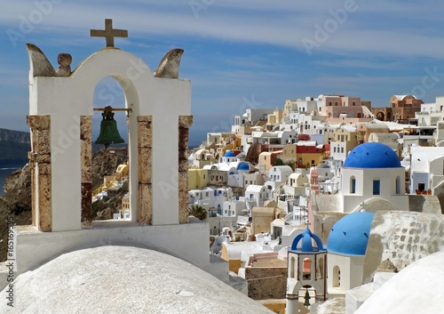 Greek Islands style white bell-tower and blue domes of the church at Oia village, Santorini island, Greece