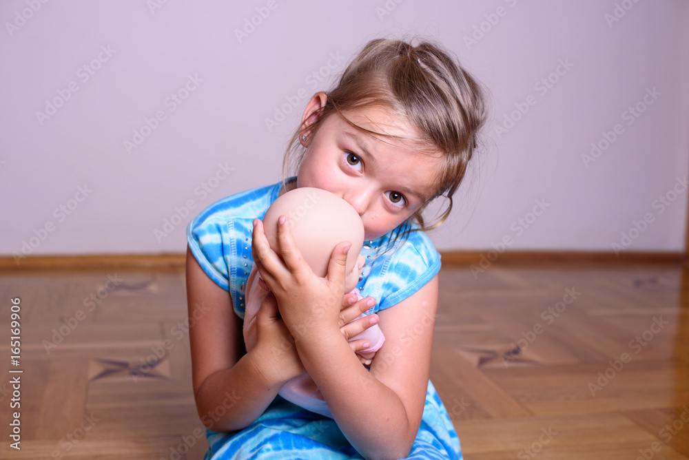 Beautiful child girl playing with a doll as mother with a newborn baby Beautiful child girl playing with a doll as mother with a newborn baby