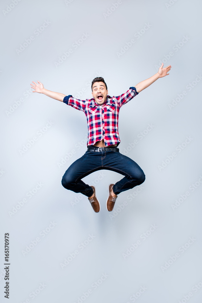 Freedom, crazy, funky, carefree, summer mood. Excited brunete guy is jumping and fooling around. He is in casual outfit on light background