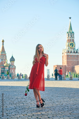 Beautiful blonde lady in red dress on Red Square in Moscow  Russia