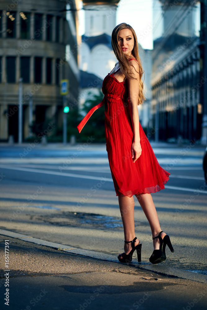 Beautiful blonde lady in red dress on White Square office center in Moscow, Russia