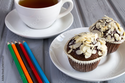 Chocolate muffins, tea and pencils on the grey wooden background photo