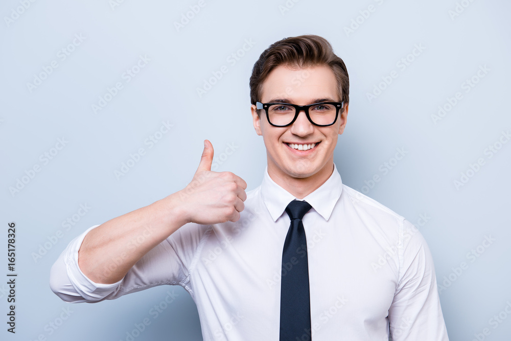 Successful excited young guy in glasses and formal wear is standing isolated on a pure background, showing thumb up sign, smiling Successful excited young guy in glasses and formal wear is standing isolated on a pure background, showing thumb up sign, smiling