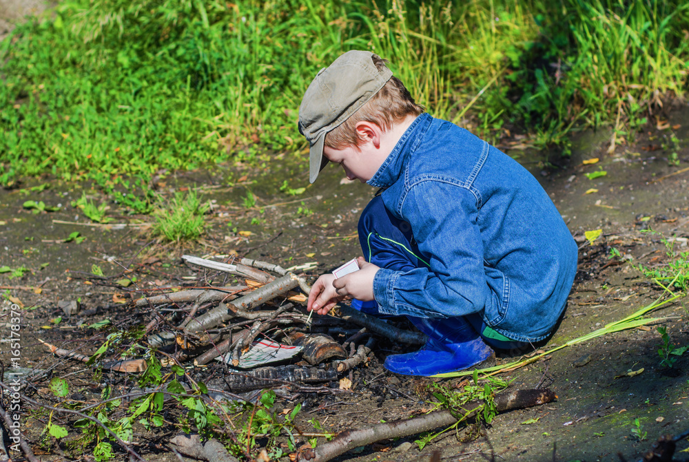 boy lights a fire in the woods boy lights a fire in the woods