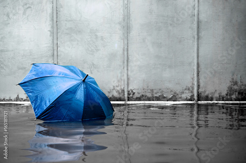 Blue umbrella floating concept. Flooded on street. .Waiting for help me after the rain. Black and white colors. Close up.