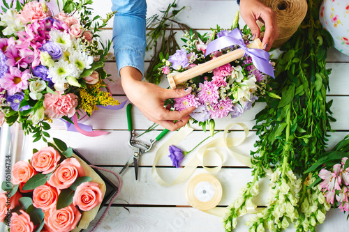 The hands of the florist close-up makes the bouquet on the white Board photo