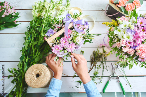 The hands of the florist close-up makes the bouquet on the white Board photo