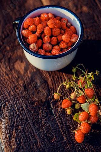 fresh wild strawberries in a Cup in the shape of a heart, symbol of love. Wooden background. The view from the top photo