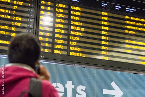 Persona guarda il tabellone dipartenze e arrivi, in stazione