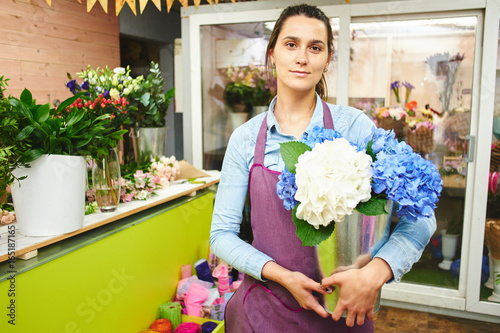 Portrait of female florist in the workshop on the background of shop Windows with flowers photo