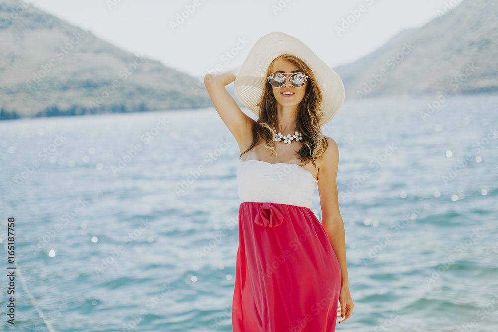 Young attractive woman with a hat and glasses poses by the sea Young attractive woman with a hat and glasses poses by the sea