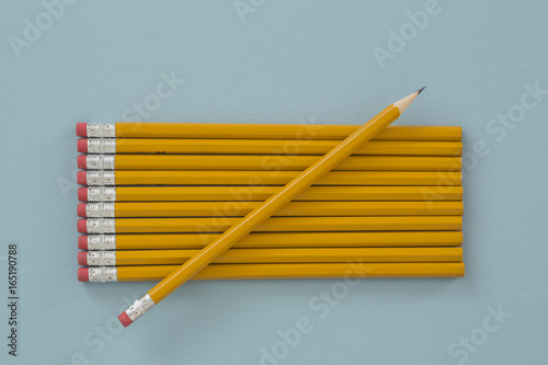 A sharpened yellow lead pencil lying on unsharpened pencils