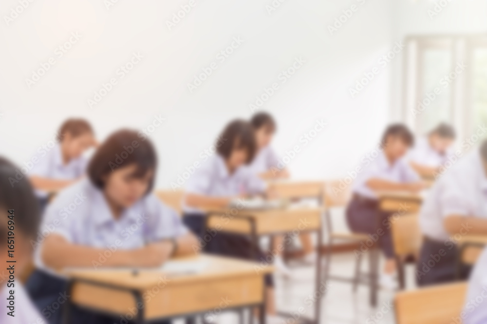 Blurred of Asian girls school students in uniform attending examination in a classroom, educational school: view of college people having exams in class on seat rows, Thailand Education